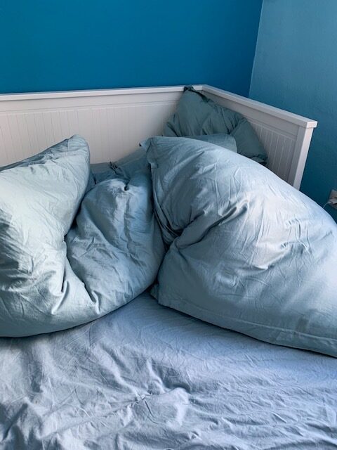 Ein Bett mit blauen Kissen und einer blauen Wand.